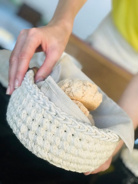 Circulo Barroco Natural Brilho - Natural Cotton Yarn Gold/Silver, 657m / 433m, 400g - A close-up of a hand holding a cream-colored crocheted basket lined with a light beige fabric, containing two rustic bread rolls.