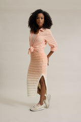 Círculo Marfim – Acrylic Gradient Cake Yarn (400 m / 200 g) - A woman modeling a light peach and white striped knit wrap dress with a side slit, styled with white sneakers against a plain light beige studio background.