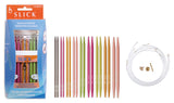 Slick knitting needle set shown with its retail box, a row of multicolored round knitting needles, and a coiled white cable with two brass tips on a plain white background.