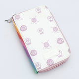 KnitPro Symfonie 2 Afghan Tunisian crochet hook set - A zip-around wallet with a white background, decorated with light purple sketches of sheep and yarn balls, and a colorful striped edge showing rainbow colors. It has a silver metal zipper and a small white patch on the front.